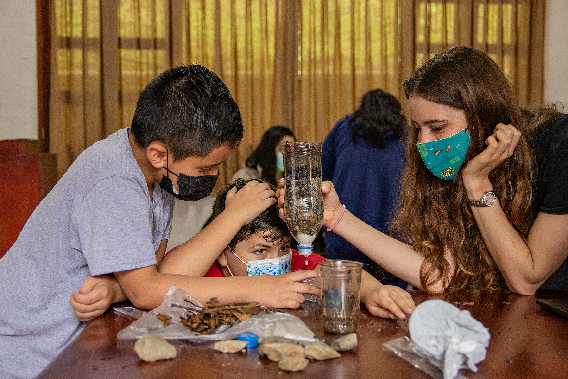 Niños y educadora explorando con experimentos en el aula del bosque